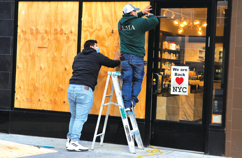 WORKERS BOARD up a store ahead of election results in the Manhattan borough of New York City earlier this week.  (photo credit: REUTERS/BRENDAN MCDERMID)