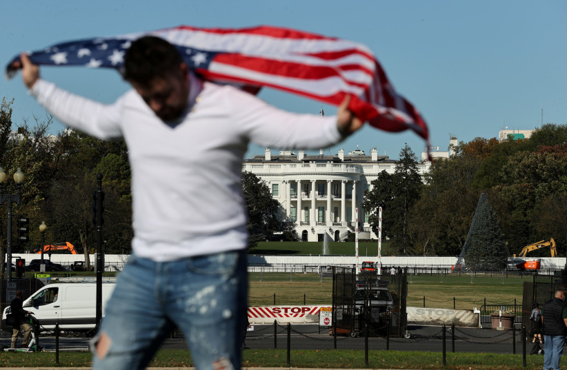 A TOURIST with a US flag poses near the White House the day after Election Day. (photo credit: JONATHAN ERNST / REUTERS)