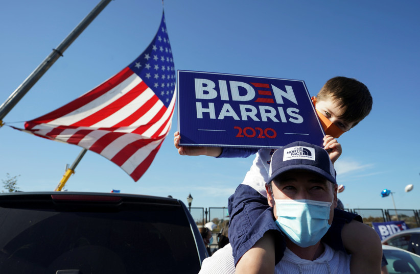 A supporter of Democratic U.S. presidential nominee Joe Biden holds a boy on his shoulders as he celebrates near the site of a planned election victory celebration after news media declared Biden to be the winner of the 2020 U.S. presidential election in Wilmington, Delaware, U.S., November 7, 2020. (photo credit: REUTERS)