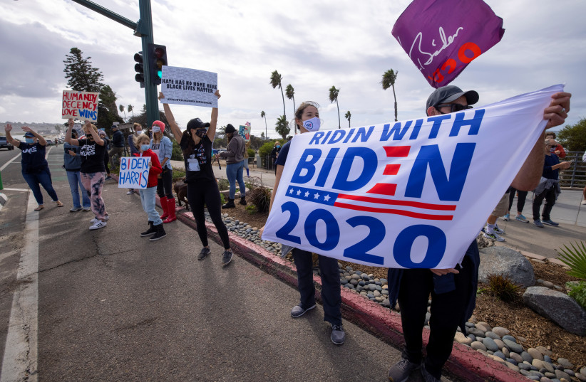 People celebrate after media announced that Democratic U.S. presidential nominee Joe Biden has won the 2020 U.S. presidential election along the 101 beach highway in Cardiff, California, US, November 7, 2020. (photo credit: MIKE BLAKE/REUTERS)
