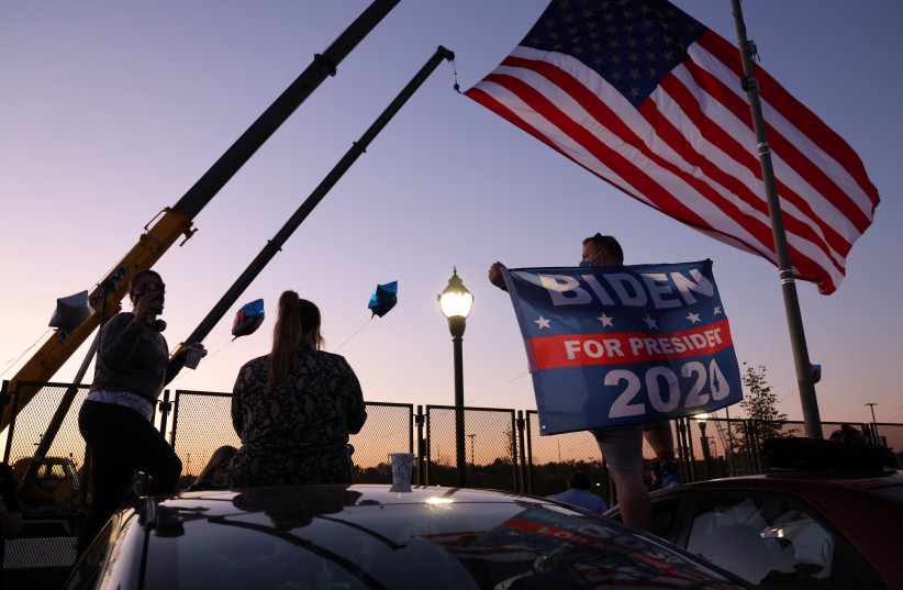 Supporters of Democratic US presidential nominee Joe Biden dance just outside the security perimeter of a planned election celebration as they await his remarks and fireworks in Wilmington, Delaware, US November 7, 2020. (photo credit: JONATHAN ERNST / REUTERS)