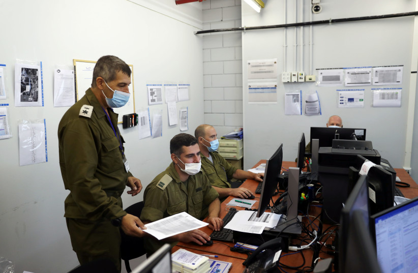 IDF soldiers work at the IDF Coronavirus Task Force Headquarters in Ramle to trace chains of infection in an effort to curb the spread of COVID-19 (photo credit: RONEN ZVULUN/REUTERS)