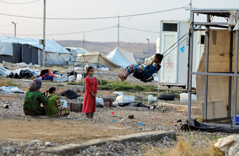 A girl plays on a makeshift swing at Hammam Al-Alil camp where displaced Iraqis prepare to be evacuated, south of Mosul (photo credit: REUTERS)