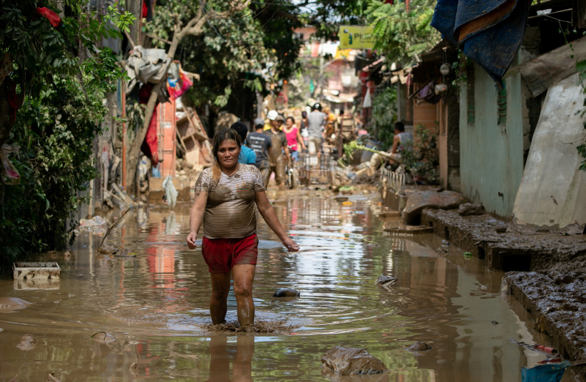A woman wades through muddy floodwater following Typhoon Vamco, in San Mateo, Rizal province, Philippines, November 13, 2020.  (photo credit: REUTERS/ELOSIA LOPEZ)
