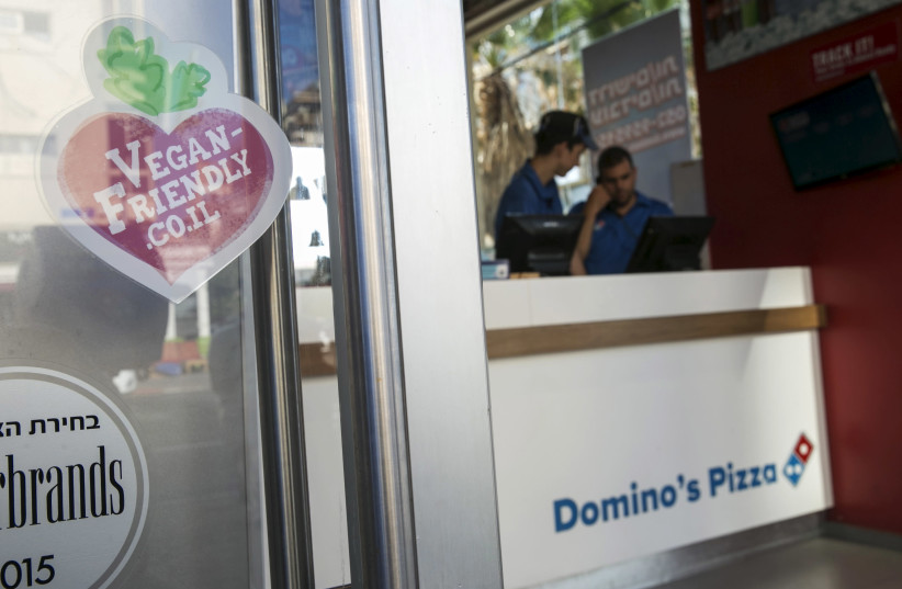 A vegan friendly sticker in seen on the door of a Domino's Pizza restaurant in Tel Aviv (credit: BAZ RATNER/REUTERS)