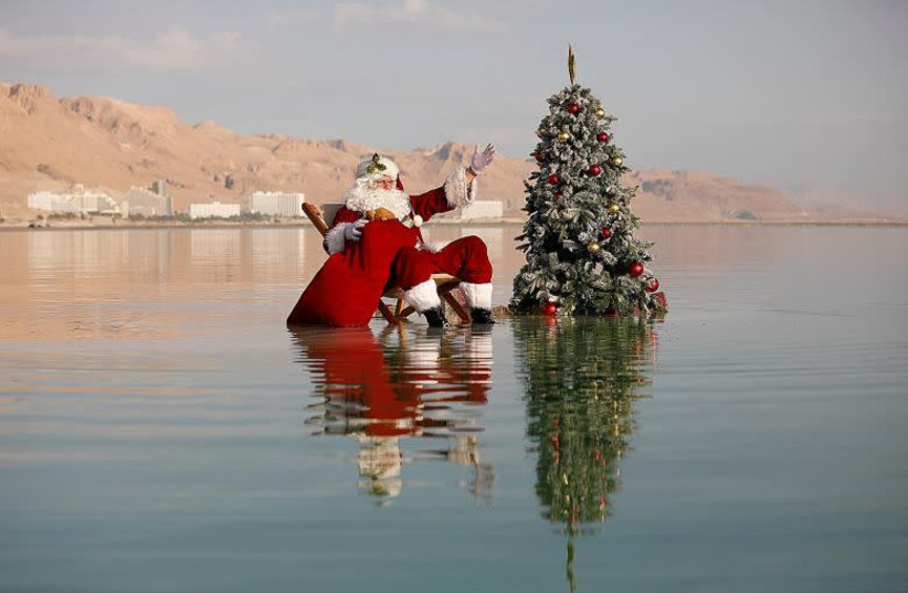 Santa Claus striking a pose for the cameras after sticking a Christmas tree on a salt formation in the Dead Sea yesterday (photo credit: REUTERS)