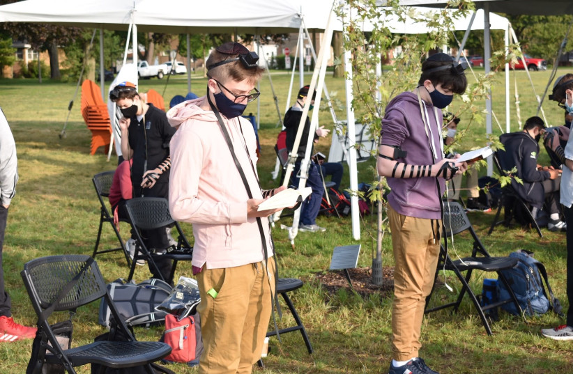 Students at the Ida Crown Jewish Academy pray in an outdoor service while wearing masks and maintaining social distance. The school has reopened with strict COVID protocols. (photo credit: EZRA LANDMAN-FEIGELSON)