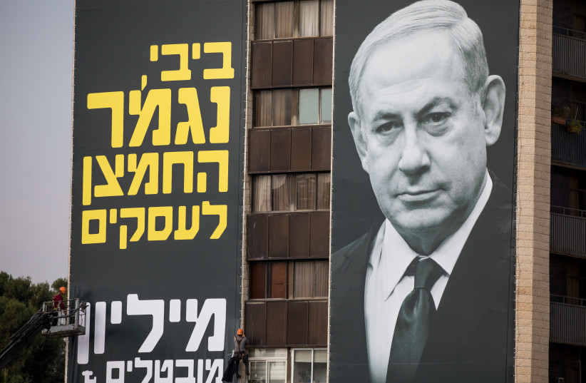 Israeli workers hang a large billboard with a picture Israeli prime minister Benjamin Netanyahu, as part of a protest of business owners against the Coronavirus Restrictions, November 12, 2020. (photo credit: YONATAN SINDEL/FLASH 90)