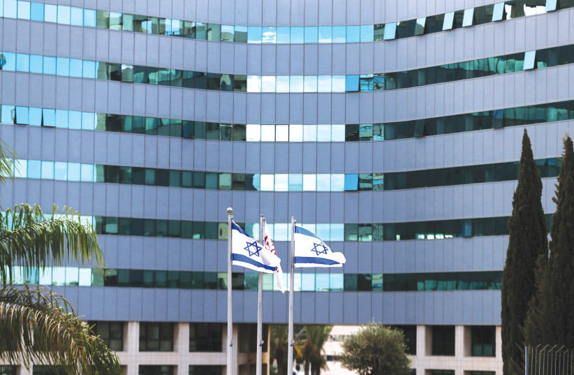 Israeli national flags flutter in front of an office tower at a business park housing high tech companies, at Ofer Park in Petah Tikva. (photo credit: RONEN ZVULUN / REUTERS)