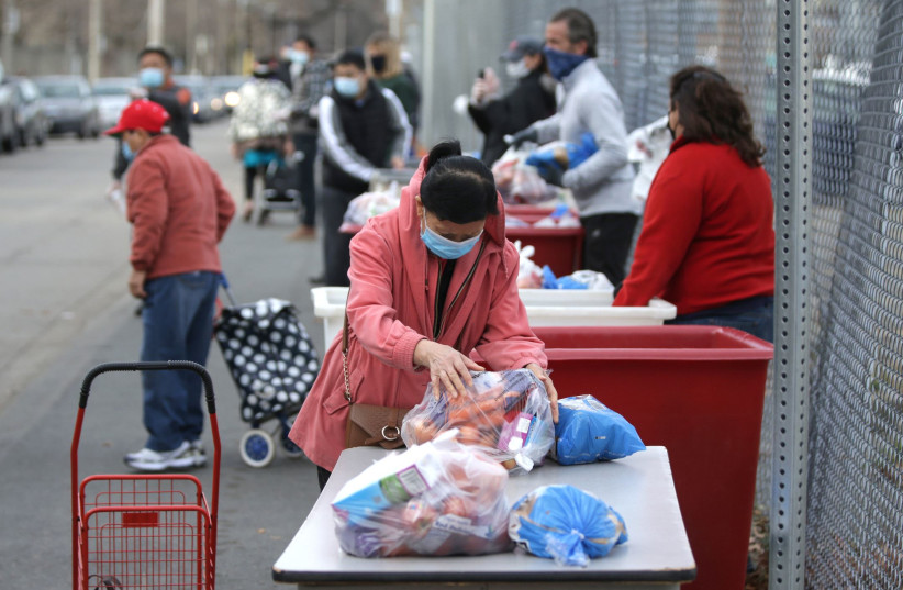 A person picks up some of the donated produce at the American Red Cross Boston Food Pantry Thanksgiving meal distribution in Boston on Nov. 21, 2020 (photo credit: JONATHAN WIGGS/THE BOSTON GLOBE VIA GETTY IMAGES)