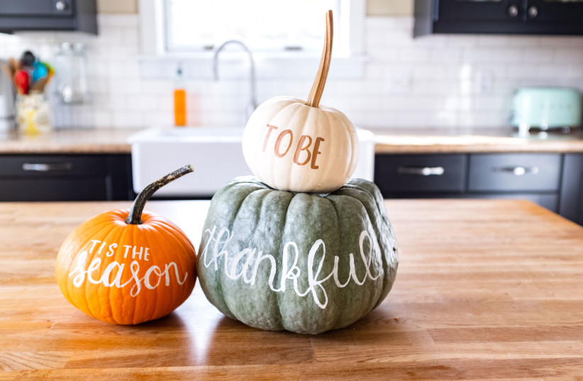 Colorful pumpkins are decorated with the handwritten words “‘tis the season to be thankful.” (credit: GETTY IMAGES)