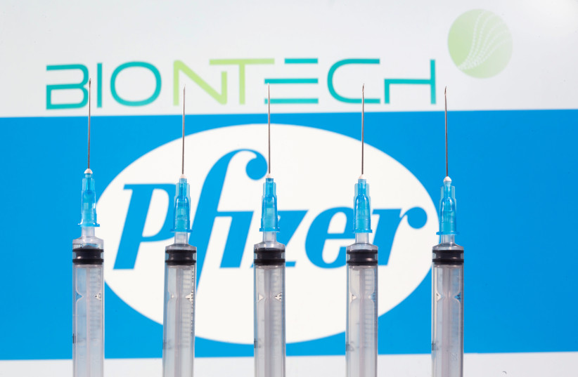 Syringes are seen in front of displayed Biontech and Pfizer logos in this illustration (photo credit: REUTERS)