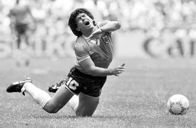 ARGENTINA’S DIEGO MARADONA falls during a World Cup match in Mexico City in 1986. (photo credit: GARY HERSHORN/REUTERS)