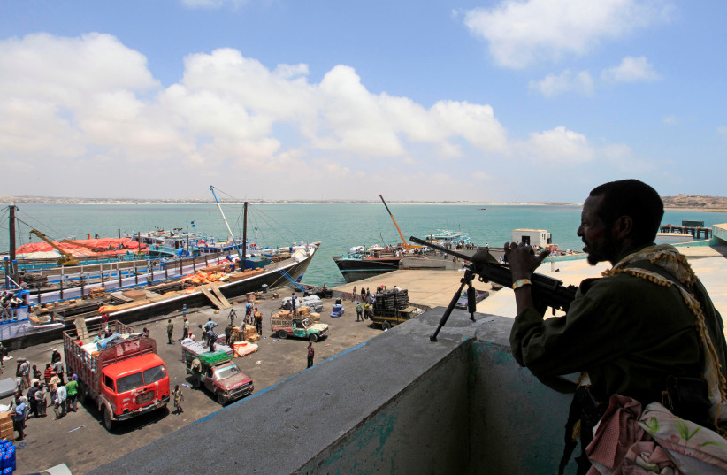 A soldier from Somalia's Ras-Kamboni paramilitary group stands guard as he monitors activities at the sea port in lower juba regions in Kismayu February 27, 2013.  (photo credit: FEISAL OMAR/REUTERS)