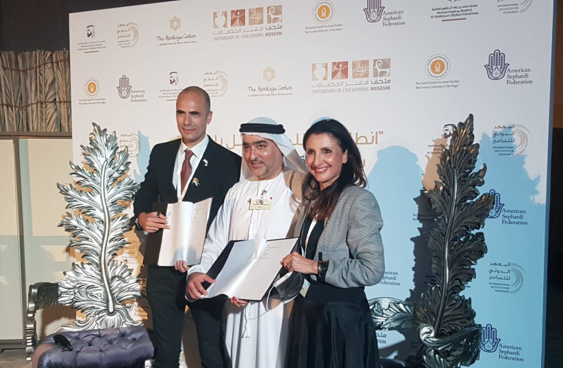 The Heritage Center for Middle East and North Africa Jewry's president Eran Taboul is seen signing an MOU with head of the Crossroads of Civilizations museum Ahmed Al Mansoori and Jerusalem Deputy Mayor Fleur Hassan-Nahoum. (photo credit: HANAN BRAND AT THE MUSEUM MOU IN DUBAI)