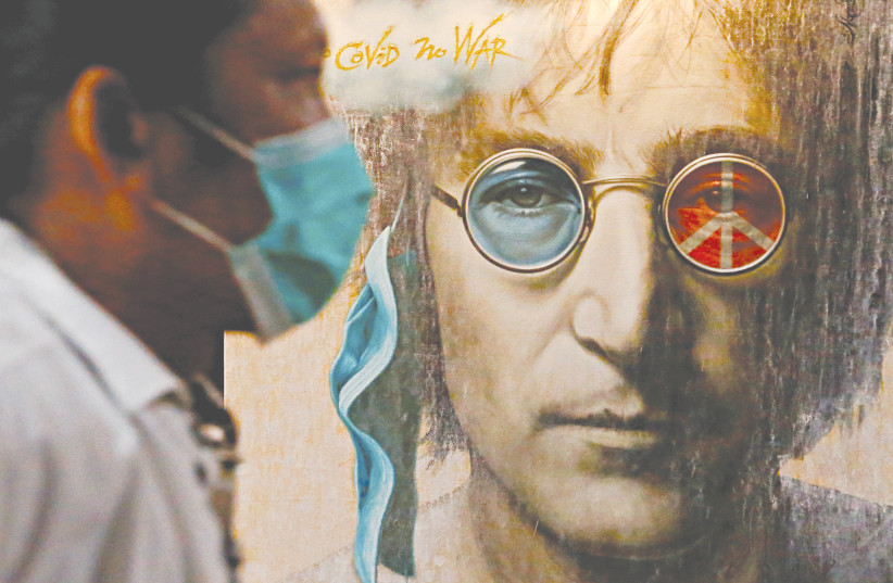 A VISITOR walks past painted art depicting John Lennon during an exhibition in Jakarta in October. (photo credit: AJENG DINAR ULFIANA/REUTERS)