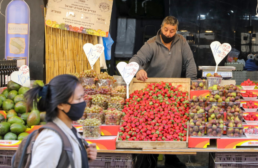 A fruit vendor is seen in Jerusalem's Mahane Yehuda amid the coronavirus pandemic, on December 8, 2020. (credit: MARC ISRAEL SELLEM/THE JERUSALEM POST)