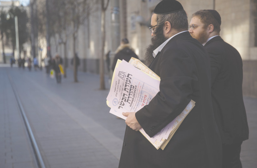REPRESENTATIVES OF the Chief Rabbinate carry kosher certificates across Jaffa Road in Jerusalem in 2019. (photo credit: HADAS PARUSH/FLASH90)
