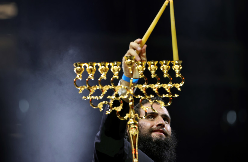 Rabbi Levi Duchman lights a candle to celebrate Hanukkah, the Jewish festival of lights, in Dubai, United Arab Emirates December 10, 2020. (photo credit: REUTERS/CHRISTOPHER PIKE)
