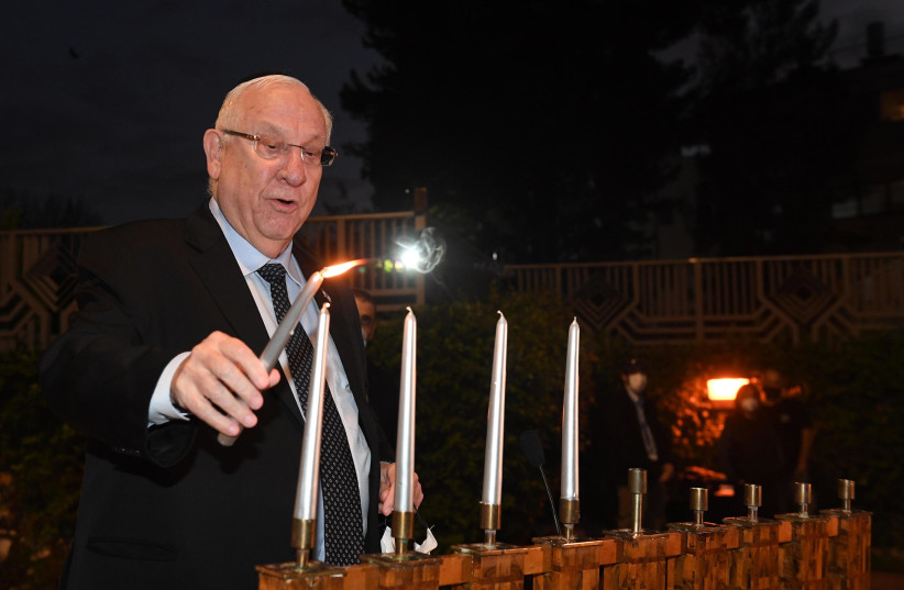 President Ruven Rivlin is seen lighing candles for the fourth night of Hanukkah on December 13, 2020. (photo credit: MARK NEYMAN/GPO)