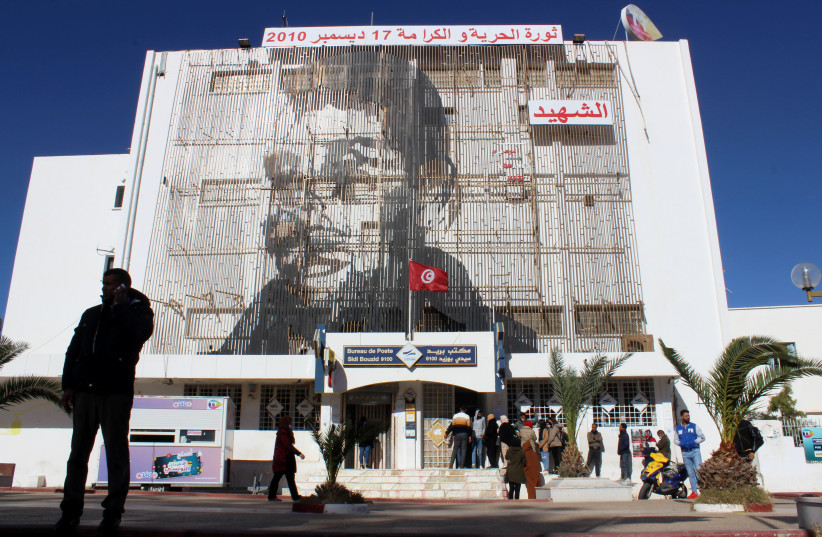 A picture of Mohamed Bouazizi, a street vendor who set himself alight 10 years ago on December 17, 2010, is displayed on the post office building in Sidi Bouzid, Tunisia December 8, 2020 (photo credit: REUTERS/ANGUS MCDOWALL)