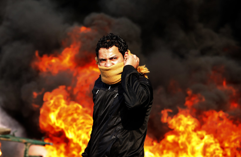 A protester stands in front of a burning barricade during a demonstration in Cairo on January 28, 2011 (photo credit: GORAN TOMASEVIC/REUTERS)