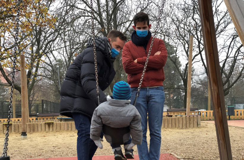 Same sex couple Adam Hanol and Marton Pal play with their four year old adopted son Andras at a playground in Budapest, Hungary, November 19, 2020. (photo credit: REUTERS/KRISZTINA FENYO)