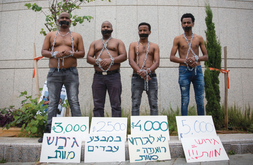 Migrants protest their potential deportation with a mock slave auction outside the Defense Ministry in Tel Aviv in 2018 (photo credit: MIRIAM ALSTER/FLASH90)