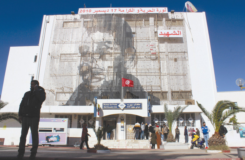 A PICTURE OF Mohamed Bouazizi, the street vendor whose self-immolation 10 years ago signaled the start of the so-called Arab Spring, is displayed on the post office building in Sidi Bouzid, Tunisia, on December 8. (credit: REUTERS/ANGUS MCDOWALL)
