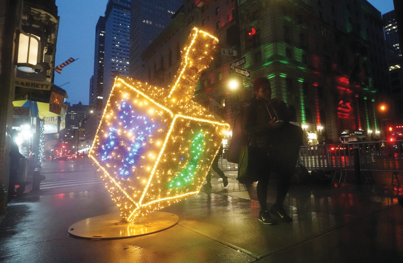 A DREIDEL made of Christmas lights sits on the sidewalk along Fifth Avenue in New York City earlier this month. (credit: CARLO ALLEGRI/REUTERS)