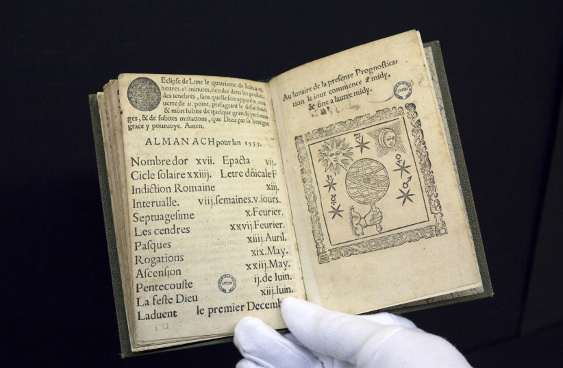 A 16th-century edition of predictions by Nostradamus, the first book to be digitised by Google from a collection of 500,000 at the Municipal Library of Lyon, is displayed by a librarian in this January 15, 2010 file picture. Amid the flat, wide fields of central France, a team of re-trained secretar (photo credit: ROBERT PRATTA/REUTERS)