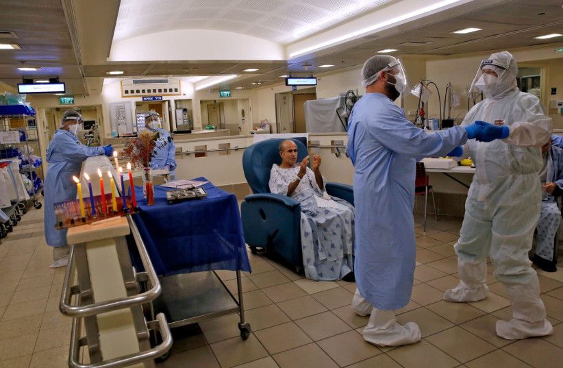 In Tel Aviv, at the Ichilov Hospital’s COVID-19 isolation ward, medical staffers lit Hanukkah candles. (photo credit: GIL COHEN-MAGEN/AFP VIA GETTY IMAGES)