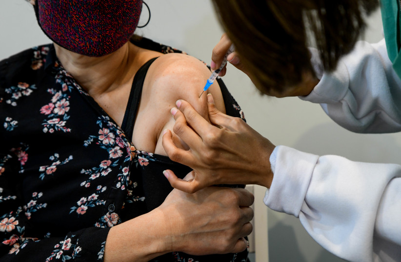 An Israeli woman receives the coronavirus vaccine (photo credit: AVSHALOM SASSONI/FLASH90)