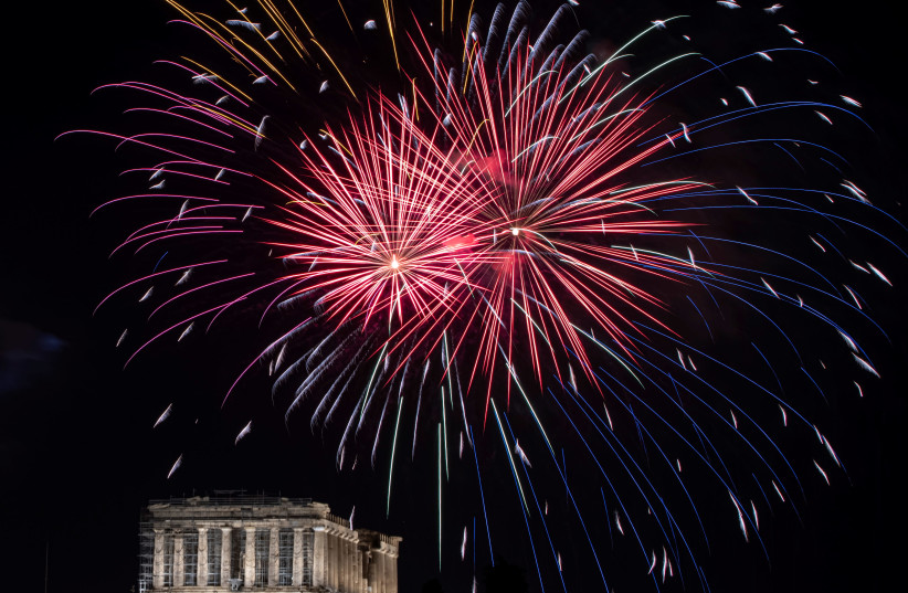 Fireworks explode over the ancient Parthenon temple atop the Acropolis hill during New Year's day celebrations, amid the coronavirus disease (COVID-19) pandemic in Athens. (photo credit: ALKIS KONSTANTINIDIS / REUTERS)