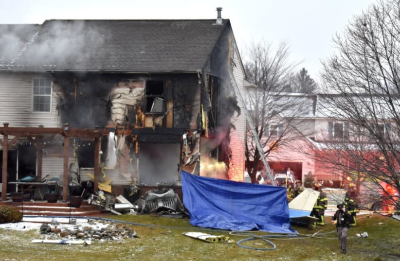 First responders investigate the scene of a plane that crashed into or near a house, setting the house on fire, on Dakota Dr. between Grispen Rd. and Cedar Mill Dr. in Lyon Twp. near the Oakland Southwest Airport, Saturday night, Jan. 2, 2021. (photo credit: TODD MCINTURF/DETROIT NEWS VIA AP)