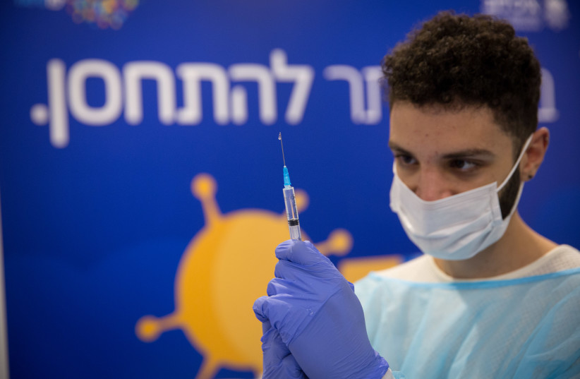 A healthcare worker prepares a vaccine at a facility operated by the Tel Aviv Sourasky Medical Center in Rabin Square, Dec. 31, 2020. (credit: MIRIAM ASTER/FLASH90)