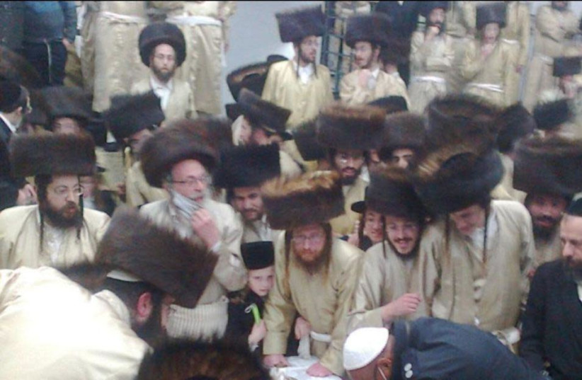 A police officer is seen surrounded by mostly-maskless hassidic men at a massive wedding in Beitar Illit that violated coronavirus lockdown restrictions. (photo credit: POLICE SPOKESPERSON'S UNIT)