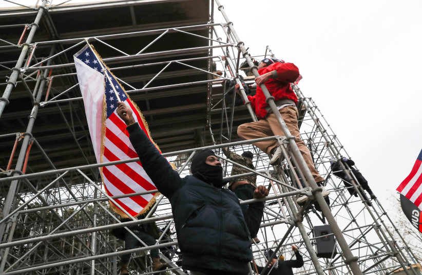 Supporters of US President Donald Trump climb a scaffolding in front of the US Capitol Building in Washington, US, January 6, 2021. (photo credit: REUTERS/LEAH MILLIS)
