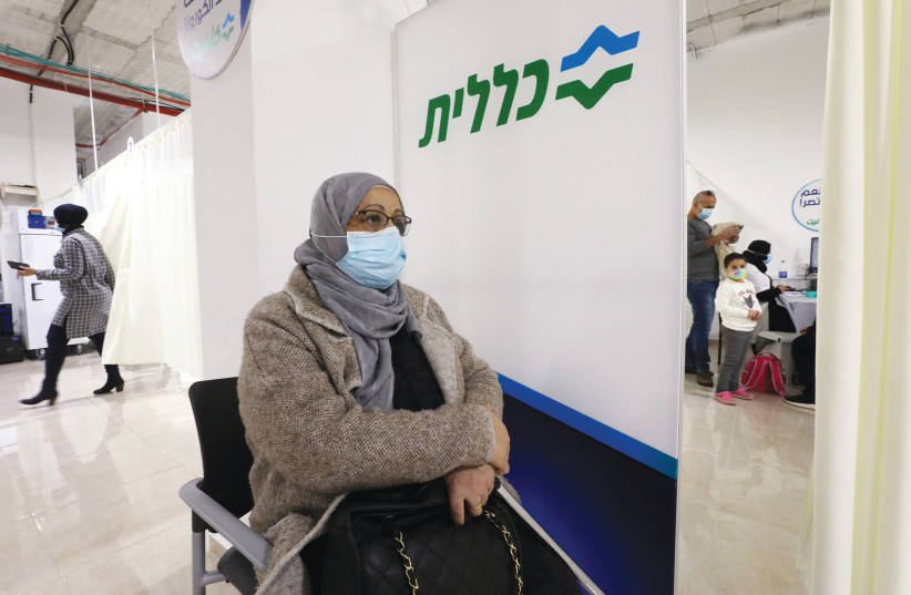 A WOMAN waits to receive a vaccination against coronavirus in Umm el-Fahm on Sunday. (photo credit: AMMAR AWAD/REUTERS)