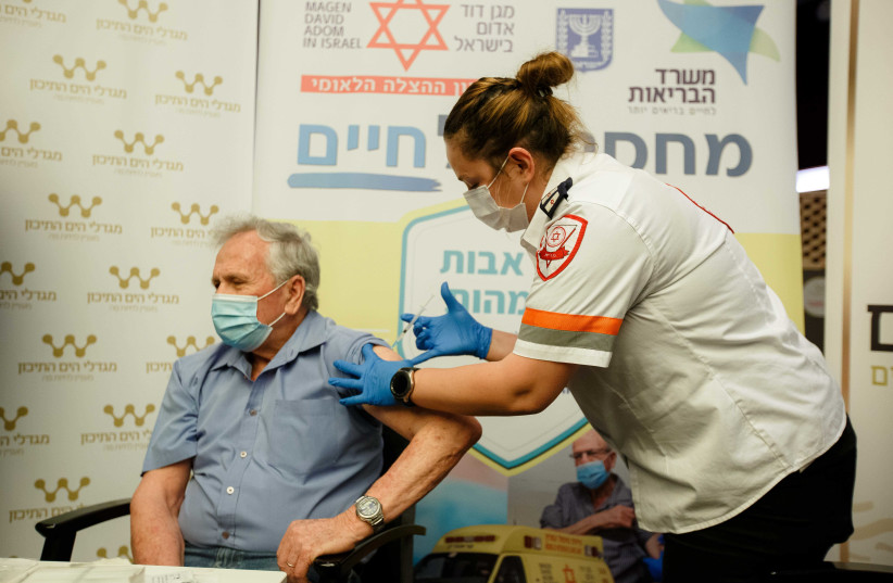 An MDA volunteer vaccinates an elderly man against the novel coronavirus. (credit: MDA)