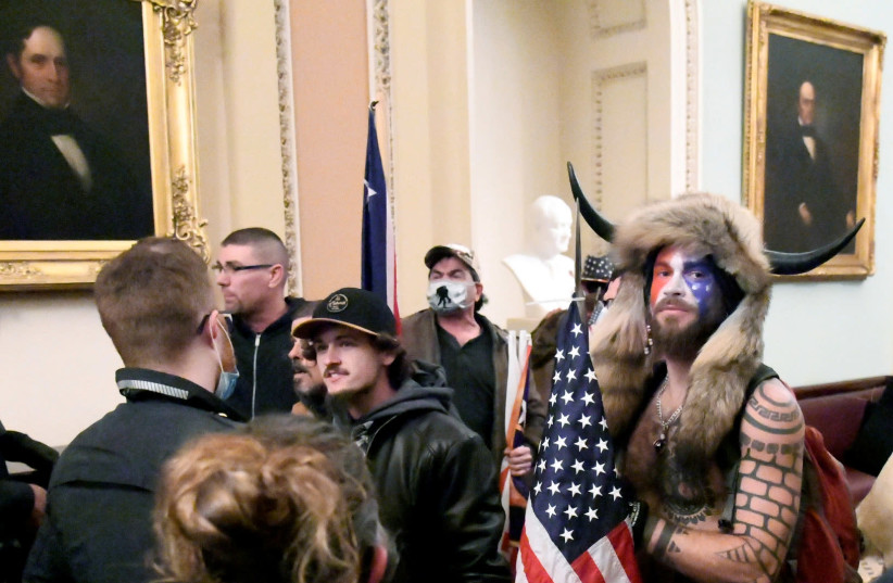 Jacob Anthony Chansley, also known as Jake Angeli, of Arizona, stands with other supporters of US President Donald Trump as they demonstrate on the second floor of the US Capitol near the entrance to the Senate after breaching security defenses, in Washington, US, January 6, 2021. (photo credit: MIKE THEILER/REUTERS)