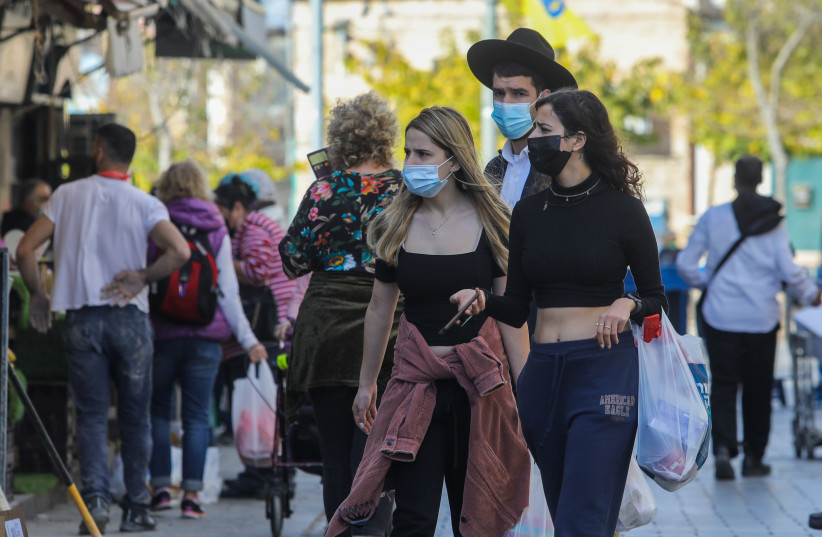 Israelis are seen walking in Jerusalem's Mahane Yehuda market amid the coronavirus pandemic, on January 12, 2021. (photo credit: MARC ISRAEL SELLEM/THE JERUSALEM POST)