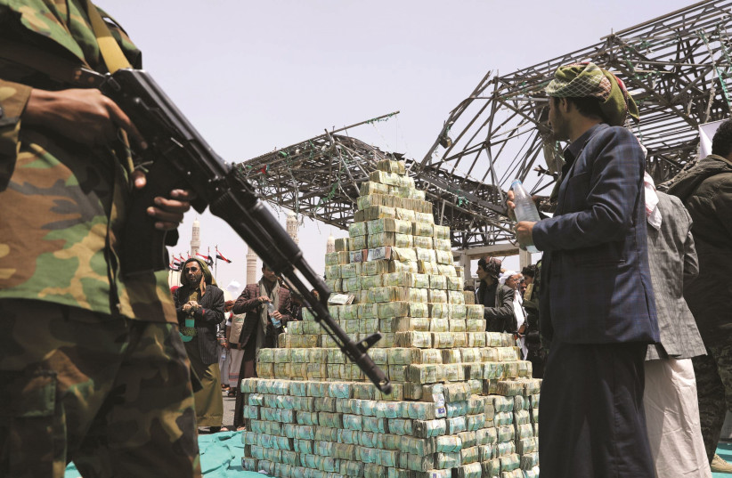 DES ADHÉRENTS HOUTHIS tiennent des billets de banque yéménites lors d'une cérémonie à Sanaa en septembre 2020 pour collecter des fournitures pour leurs combattants combattant les forces gouvernementales. (crédit photo : KHALED ABDULLAH/REUTERS)