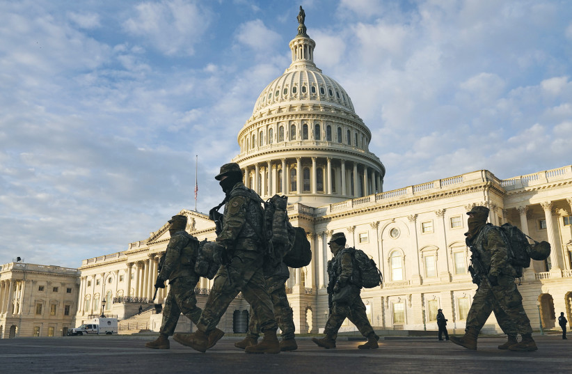 NATIONAL GUARD members walk in front of the US Capitol on Thursday, as tension continues ahead of President-elect Joe Biden’s inauguration next week. (photo credit: JOSHUA ROBERTS / REUTERS)