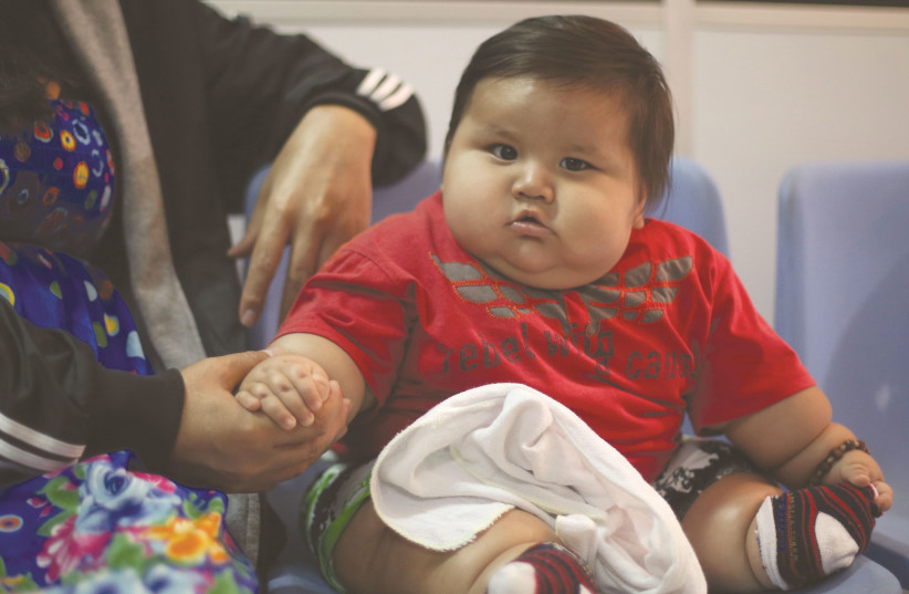 An eight-month-old boy weighing 20 kg. sits at a clinic for the obese in Bogota, Colombia (photo credit: JOHN VIZCAINO/REUTERS)