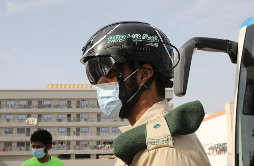 A United Arab Emirates police officer wears a smart helmet to check the temperature of workers during the outbreak of COVID-19 in Dubai on April 23, 2020. (photo credit: AHMED JADALLAH/REUTERS)