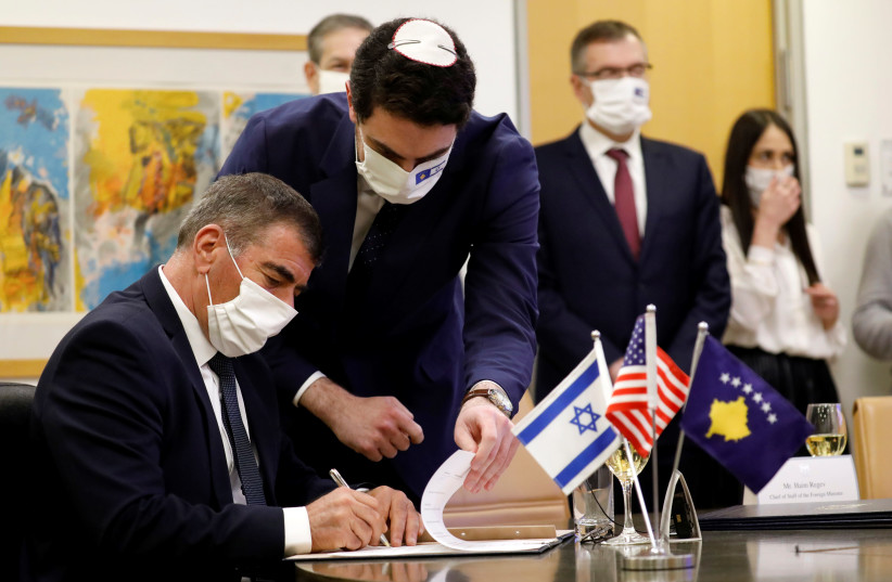 Israel's Foreign Minister Gabi Ashkenazi signs the agreement establishing diplomatic relations between Israel and Kosovo during a virtual ceremony with Kosovo's Foreign Minister Meliza Haradinaj Stublla, in the Israeli foreign ministry in Jerusalem February 1, 2021. (photo credit: AMIR COHEN/REUTERS)