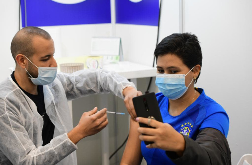 Israelis receive the coronavirus vaccine in Tel Aviv after the Health Ministry announced that anyone over the age of 16 can now be vaccinated, Feb. 4, 2021. (photo credit: AVSHALOM SASSONI/MAARIV)
