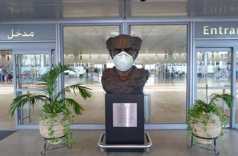 A face mask is seen on the bust of David Ben-Gurion at Ben-Gurion Airport. (photo credit: ANTON DELIN)