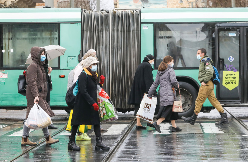 Pedestrians walk past a bus in downtown Jerusalem on January 18, 2021. (photo credit: MARC ISRAEL SELLEM)